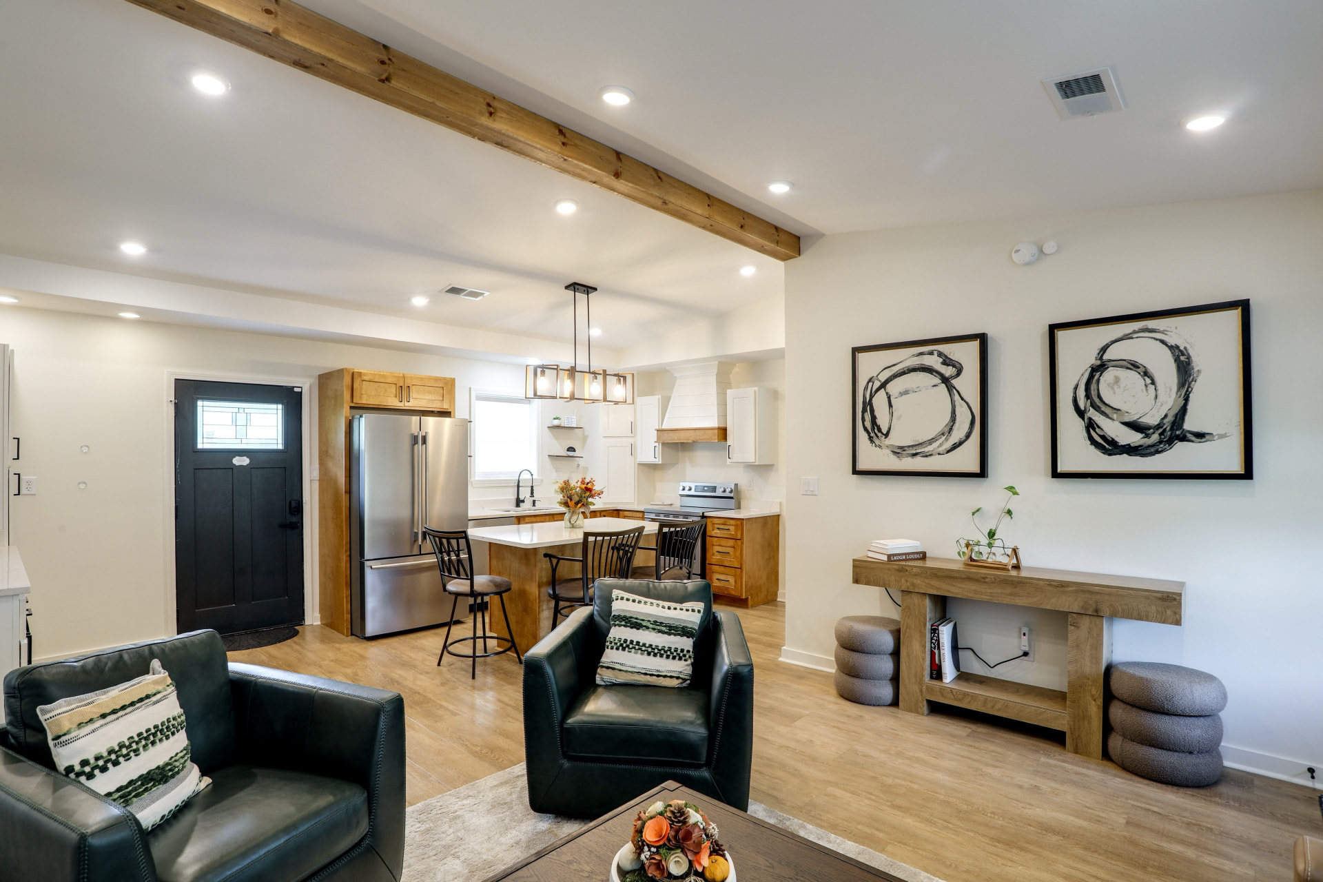Open living area at Cedarstone Retreat looking toward the kitchen island with bar stools, wood beam ceiling, and console table