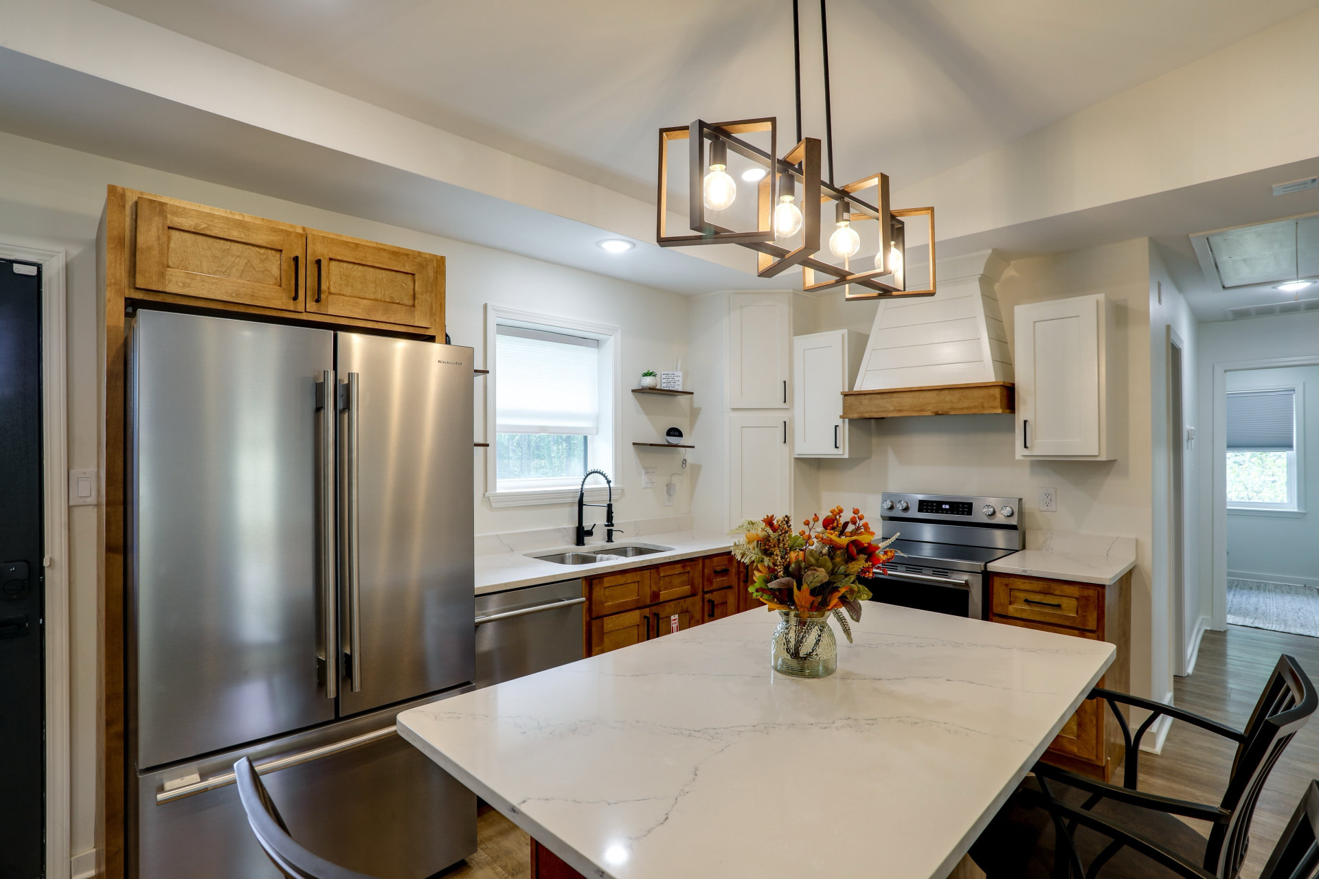 Kitchen at Cedarstone Retreat with a quartz island, four bar stools, stainless appliances, and wood and white cabinetry