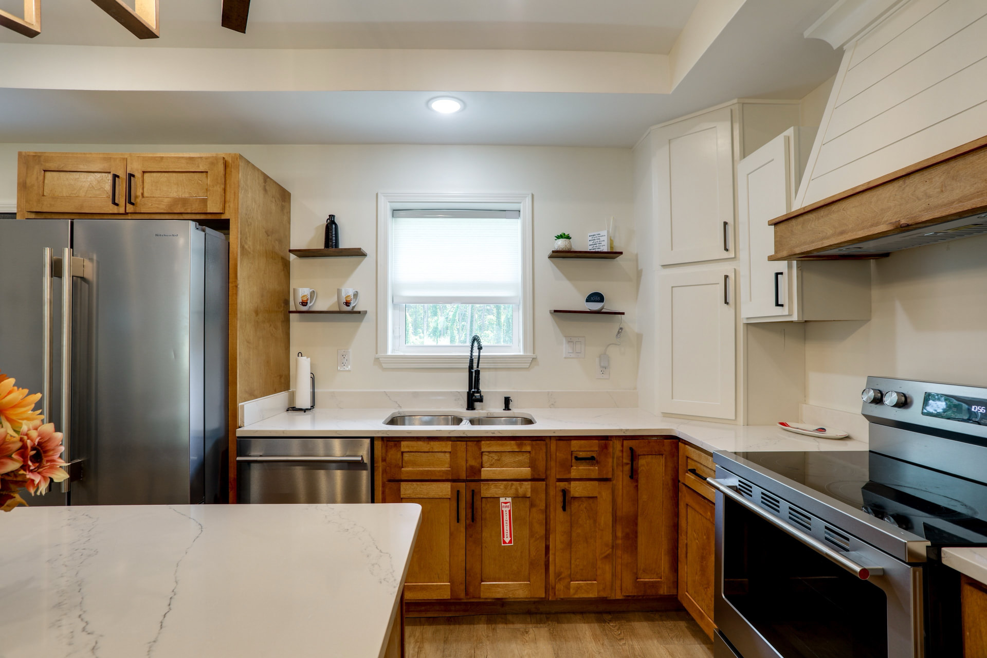 Kitchen at Cedarstone Retreat with wood and white cabinetry, quartz counters, farmhouse range hood, and stainless appliances