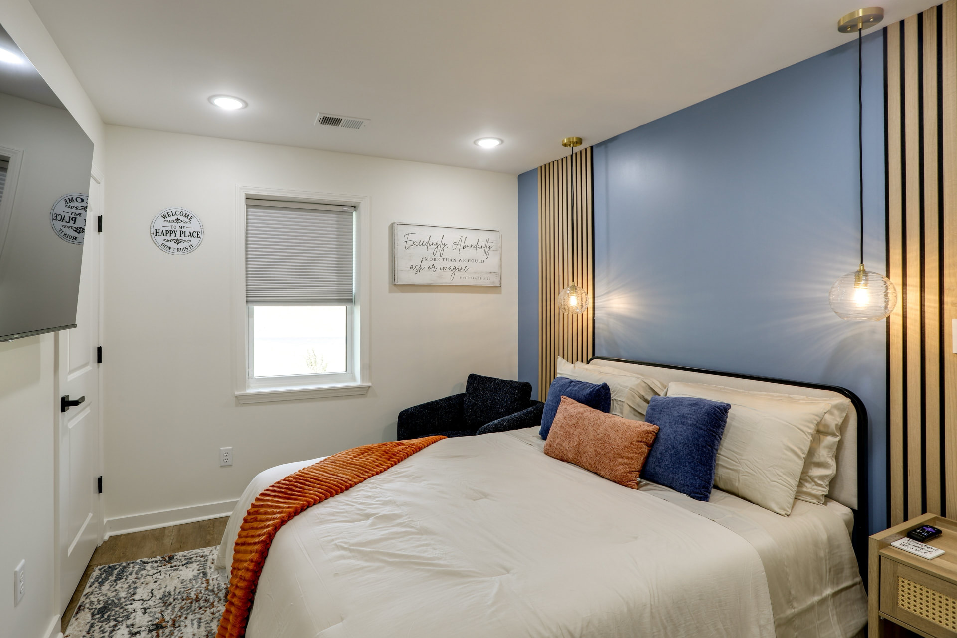 Queen bedroom at Cedarstone Retreat with a blue accent wall, wood slat detail, and pendant lighting