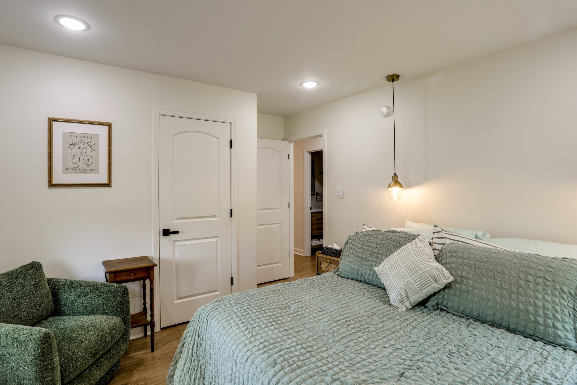 Sage-and-green bedroom at Cedarstone Retreat with one queen bed and a green armchair