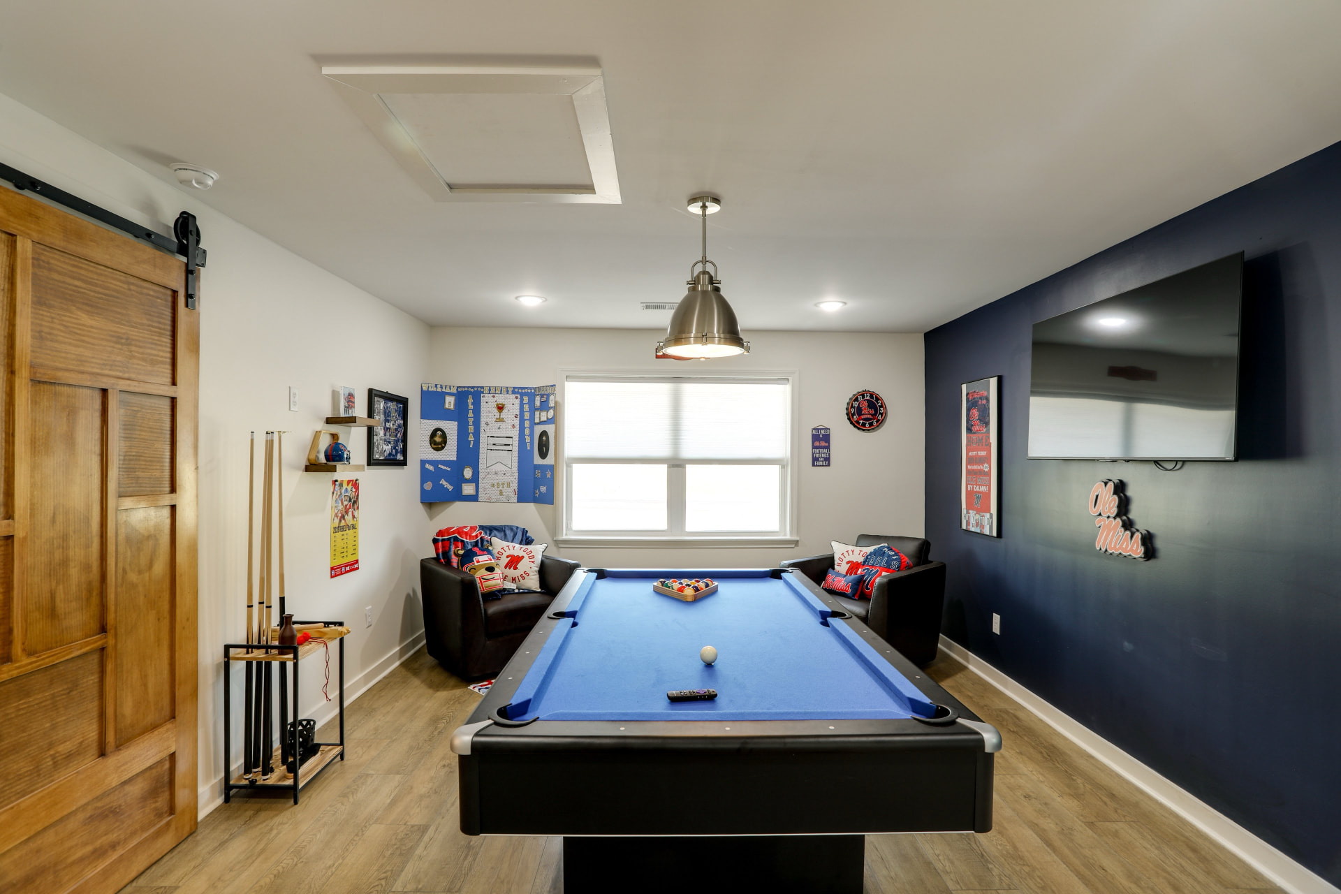 Ole Miss themed game room at Cedarstone Retreat with a pool table, seating, and a large TV for watching the Rebels