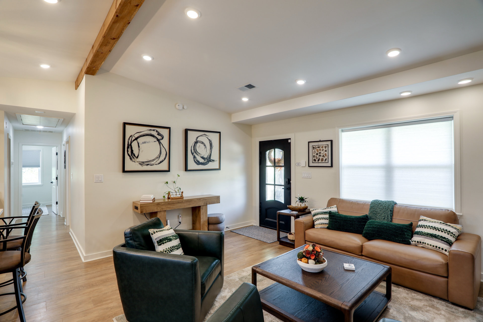 Living room at Cedarstone Retreat with a leather sofa, swivel chairs, framed art, and the front entry door