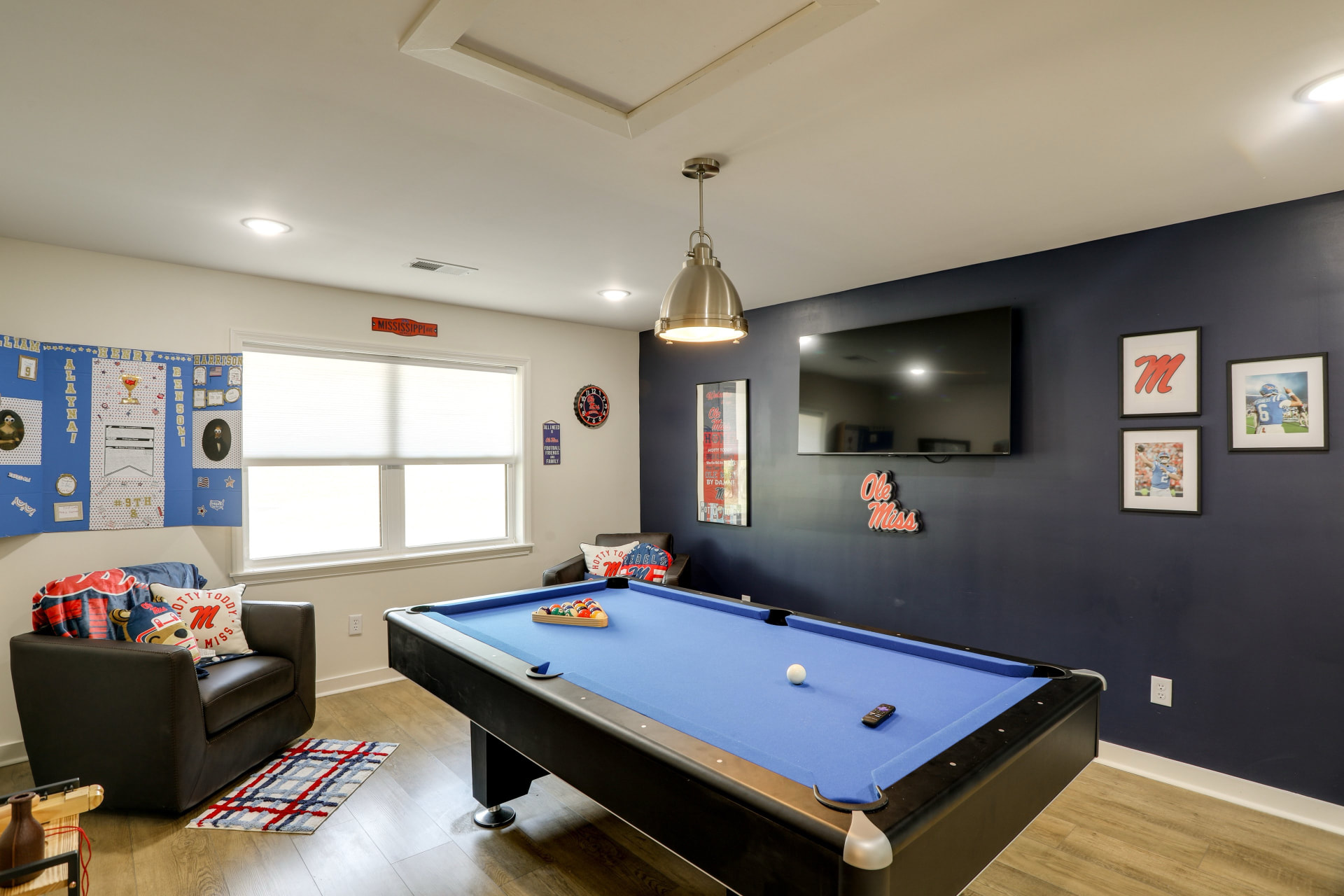 Angled view of the Cedarstone Retreat game room with pool table, lounge chairs, and Ole Miss wall decor